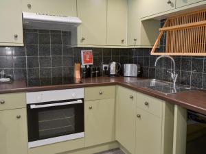 een keuken met witte kasten en een spoelbak bij Rockfish Cottage in Brixham