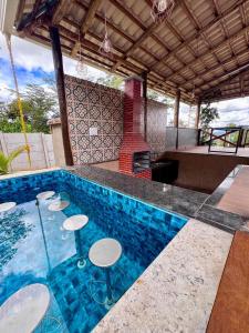 a pool with chairs and a table and a fireplace at Sítio Recanto da Serra in Mateus Leme