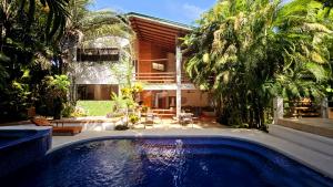 a swimming pool in front of a house with trees at Dreamcatcher Hotel - Live the Dream of Santa Teresa in Santa Teresa Beach
