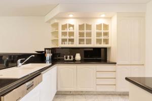 a kitchen with white cabinets and black counter tops at Mirage Resort Villa 409 with access to Sheraton Facilities in Port Douglas