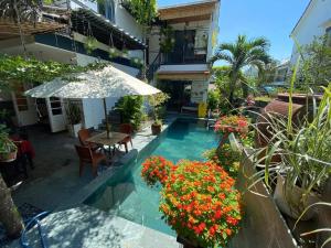 a patio with a table and an umbrella and flowers at An Bang Star Homestay in Hoi An