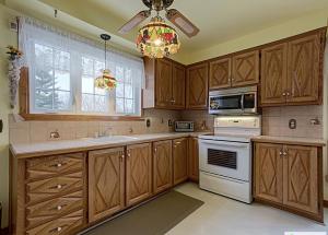 a kitchen with wooden cabinets and a chandelier at 2 beds in a private room B with a free parking -15 min from downtown in Longueuil +7 photos