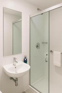 a bathroom with a sink and a glass shower at Stop Inn Antonio Carlos in Belo Horizonte