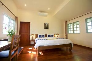 a bedroom with a bed and a desk and windows at Monoceros Resort in Mae Rim