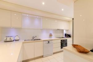 a white kitchen with a sink and a dishwasher at Mirage Resort Villa 438 with access to Sheraton Facilities in Port Douglas