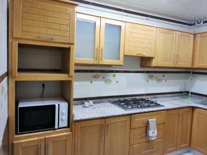 a small kitchen with wooden cabinets and a microwave at Djawed hôt in Alger