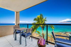 a table and chairs on a balcony with a view of the ocean at KIHEI SURFSIDE, #501 condo in Wailea