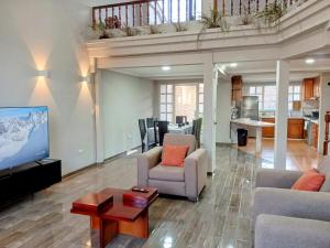 a living room with a couch and a tv and a table at Casa amplia con espacio verde in Cuenca