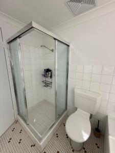 a white bathroom with a shower and a toilet at Discover Cronulla - Beach Escape in Cronulla +11 photos
