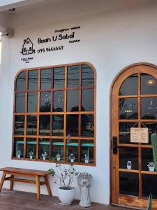 a building with a wooden door and a bench at Baan U Sabai Poshtel (บ้านอยู่สบาย พอสเทล) in Manorom