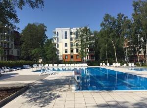 une piscine avec des chaises et un bâtiment en arrière-plan dans l'établissement Apartament Manhattan, à Kołobrzeg