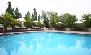a pool with chairs and umbrellas in it at Vivanta Bengaluru Residency Road in Bangalore