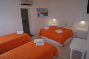 zwei Betten in einem Zimmer mit orangefarbenen Laken in der Unterkunft Hotel Milena in Mykonos Stadt