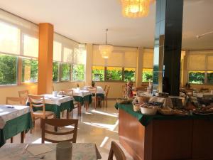 un ristorante con tavoli e sedie e una persona seduta a un tavolo di Hotel Plutone a Cervia