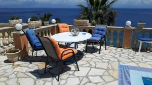 un patio con mesa, sillas y el océano en Oniro Villas, en Agios Ioannis Peristerion