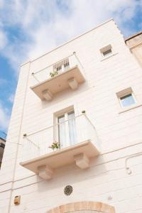un edificio blanco con 2 balcones y flores. en B&B Donnapasqua, en Polignano a Mare