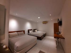 a hotel room with two beds and a television at Cactus Guest House Borobudur in Borobudur