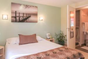 una camera da letto con un letto e un dipinto sul muro di Hôtel Restaurant de la Dore a Vertolaye