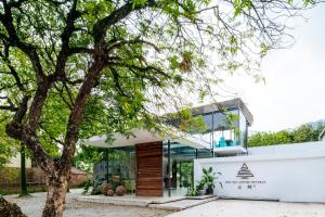 a house with glass walls and a tree at Qingyuan Zhilin Hot Spring Bed and Breakfast in Qingyuan