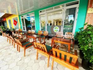 a group of wooden tables and chairs in a restaurant at GREEN Hotel & Coffee in Bak Kan