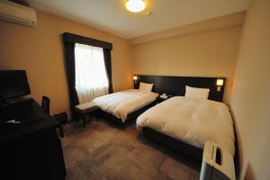 a hotel room with two beds and a window at Dormy Inn Express Koriyama in Koriyama