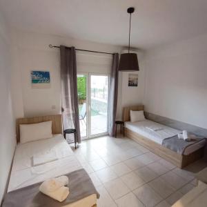 a bedroom with two beds and a balcony at R&T Apartments in Kallithea Halkidikis