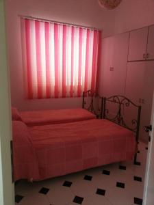 a bedroom with two beds and a window with red sheets at Alphi's Home Nebida in Nebida