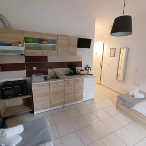 a kitchen with wooden cabinets and a bed in a room at R&T Apartments in Kallithea Halkidikis