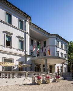 un grande edificio bianco con bandiere di fronte di Grand Hotel Terme a Riolo Terme