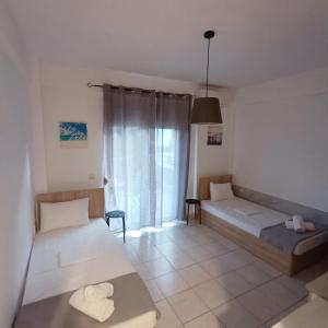 a living room with two beds and a window at R&T Apartments in Kallithea Halkidikis