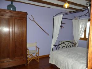 a bedroom with a canopy bed and a chair at Casa Rural Iturrieta in Adiós