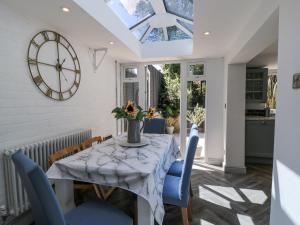 a dining room with a table with blue chairs and a clock at Delightful Dorset House By Wareham River in Wareham