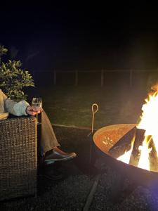 a woman holding a glass of wine next to a fire at Panda's Patch Dunsborough in Dunsborough