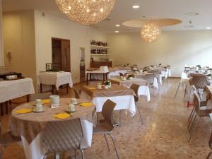 a dining room with white tables and chairs and chandeliers at Hotel Condor in Milano Marittima
