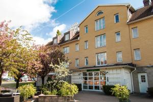 a large brick building with trees in front of it at Hotel Mölndals Bro in Mölndal