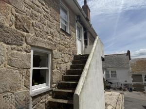 un edificio de piedra con una escalera junto a una ventana en Seagulls Nest, en St Ives 9 fotos más