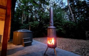 a stove with a fire next to a trash can at Glampingtent Bosgenot in Zedelgem