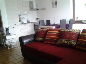 ein Wohnzimmer mit einem roten Sofa und einer Küche in der Unterkunft Holiday Home Casa Stefi in Piazzogna