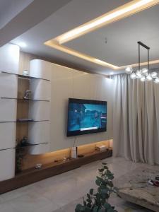 a living room with a flat screen tv on a wall at De-Santos in Mama