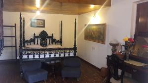 a room with a bed with two chairs and a table at The Red House in Ooty