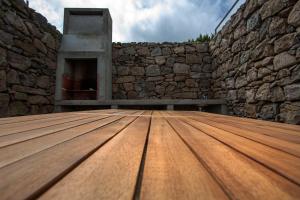 a wooden floor in front of a stone wall at Casa do Simão in Nordeste