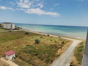 a road leading to a beach with a building and the ocean at Răsărit la epava in Costinesti