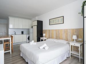 ein Schlafzimmer mit einem großen weißen Bett und einer Küche in der Unterkunft Great terrace sea views - Wifi By Canariasgetaway in Las Palmas de Gran Canaria