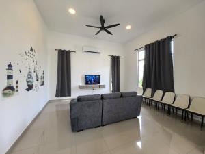 a living room with a couch and a ceiling fan at Padang Serai Wangi Homestay 91 in Padang Serai