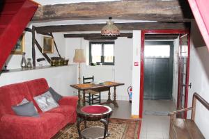 ein Wohnzimmer mit einem roten Sofa und einem Tisch in der Unterkunft Gîte les beaux-arts in Ronzon
