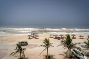 a beach with cars and palm trees and umbrellas at Luxury Villa Beach Front in Salalah
