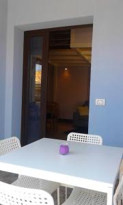 un tavolo bianco con sedie e ciotola viola di Sky Apartments - Catania City Center a Catania