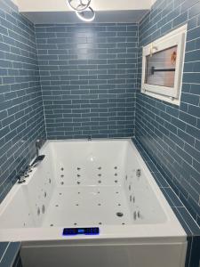 ein blau gefliestes Badezimmer mit einer weißen Badewanne in der Unterkunft Maison vacances in Saint-Mammès