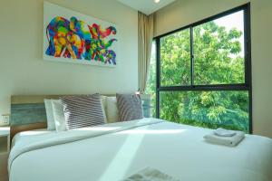 Un dormitorio con una cama grande y una ventana en C130 Steps to Beach 1BR Condo Gym, Pool & Sauna, en Rawai Beach 24 fotos más