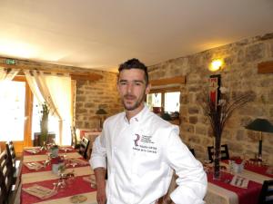 a man in a white shirt standing in front of a table at Logis Hôtel restaurant Auberge de la Cascade in Sainte-Énimie